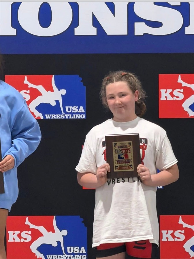 Ellsworth wrestler holding a state wrestling award on the podium